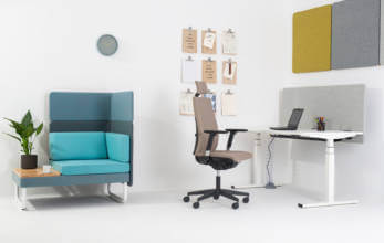 nowoczesny fotel biurowy przy białym biurku obok kolorowego siedziska ze stolikiem