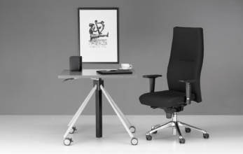 czarny wysoki fotel biurowy przy eleganckim biurku na kółkach
